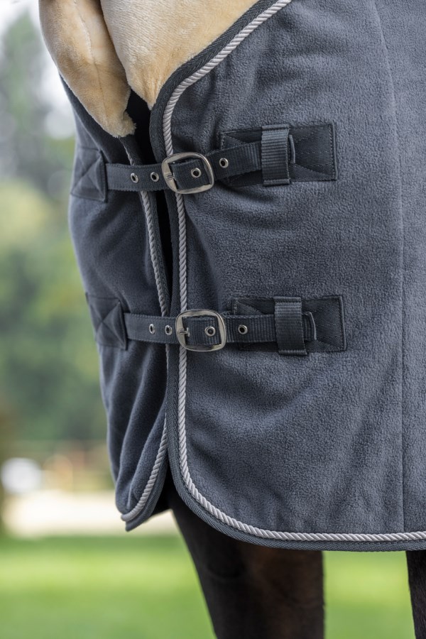 Nahaufnahme einer graphitfarbenen Fleecedecke am Pferd mit doppeltem Brustverschluss und silberner Zierkordel.