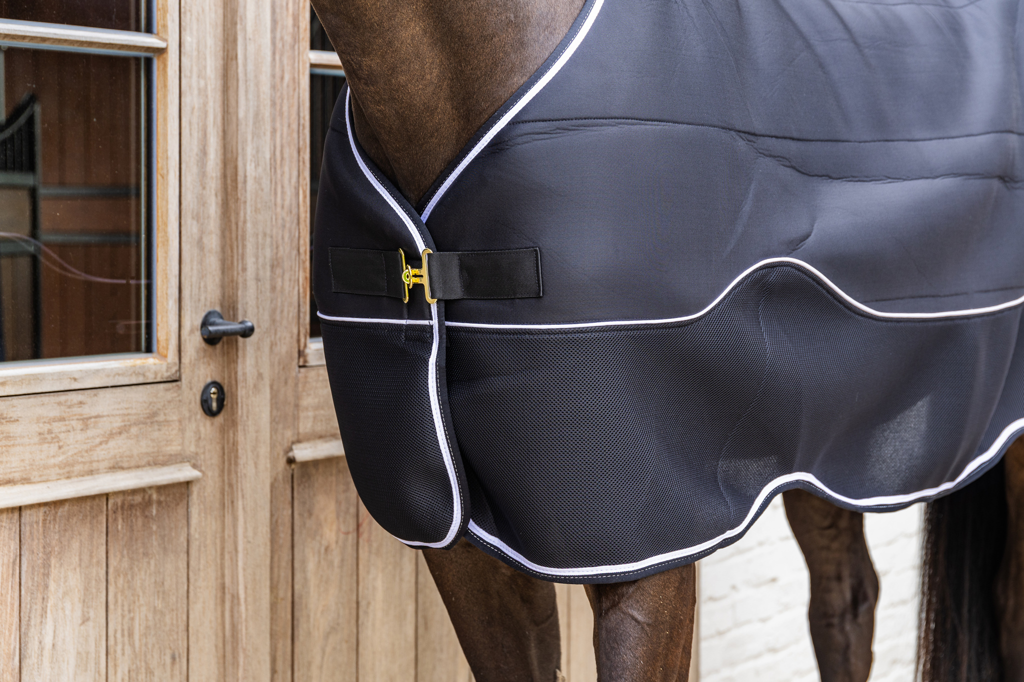 KENTUCKY® HORSEWEAR Turnout Rug Comfort 3D Fleece Liner, schwarz Nahaufnahme der schwarzen Turnoutdecke Comfort 3D Fleece Liner am Pferd mit goldenem Verschluss und weißer Biese