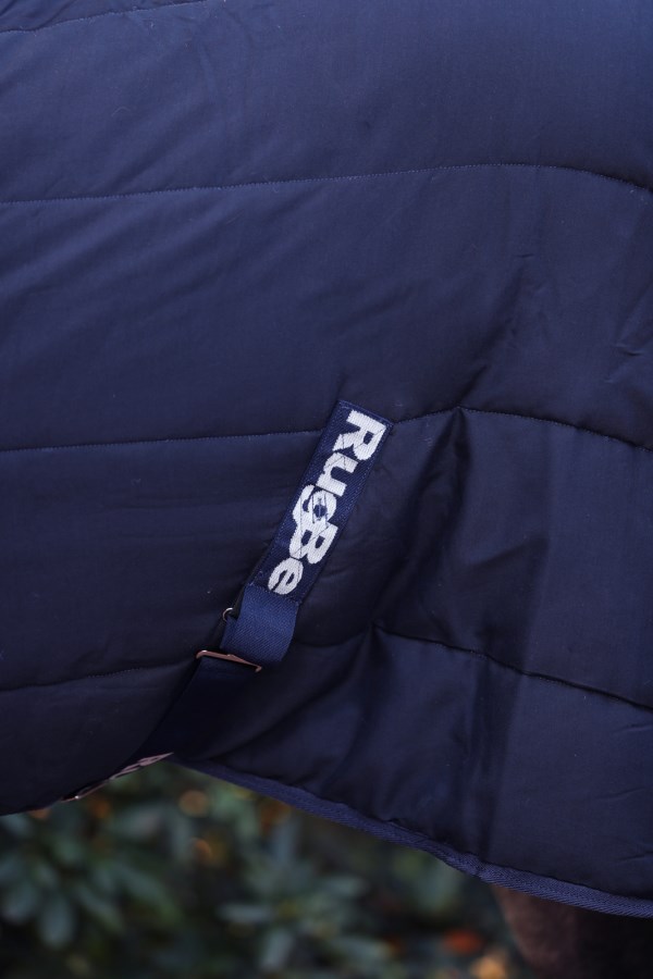 Detailansicht der dunkelblauen und gesteppten Kerbl Stalldecke RugBe mit aufgenähtem Marken-Logo.