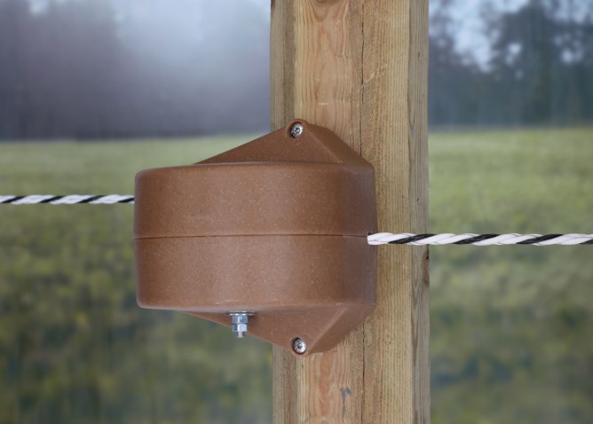 Braunes AKO FLEXIGATE Tor-Set mit Seilaufroller, an einem Holzpfosten befestigt, mit schwarz-weißem Weidezaunseil.