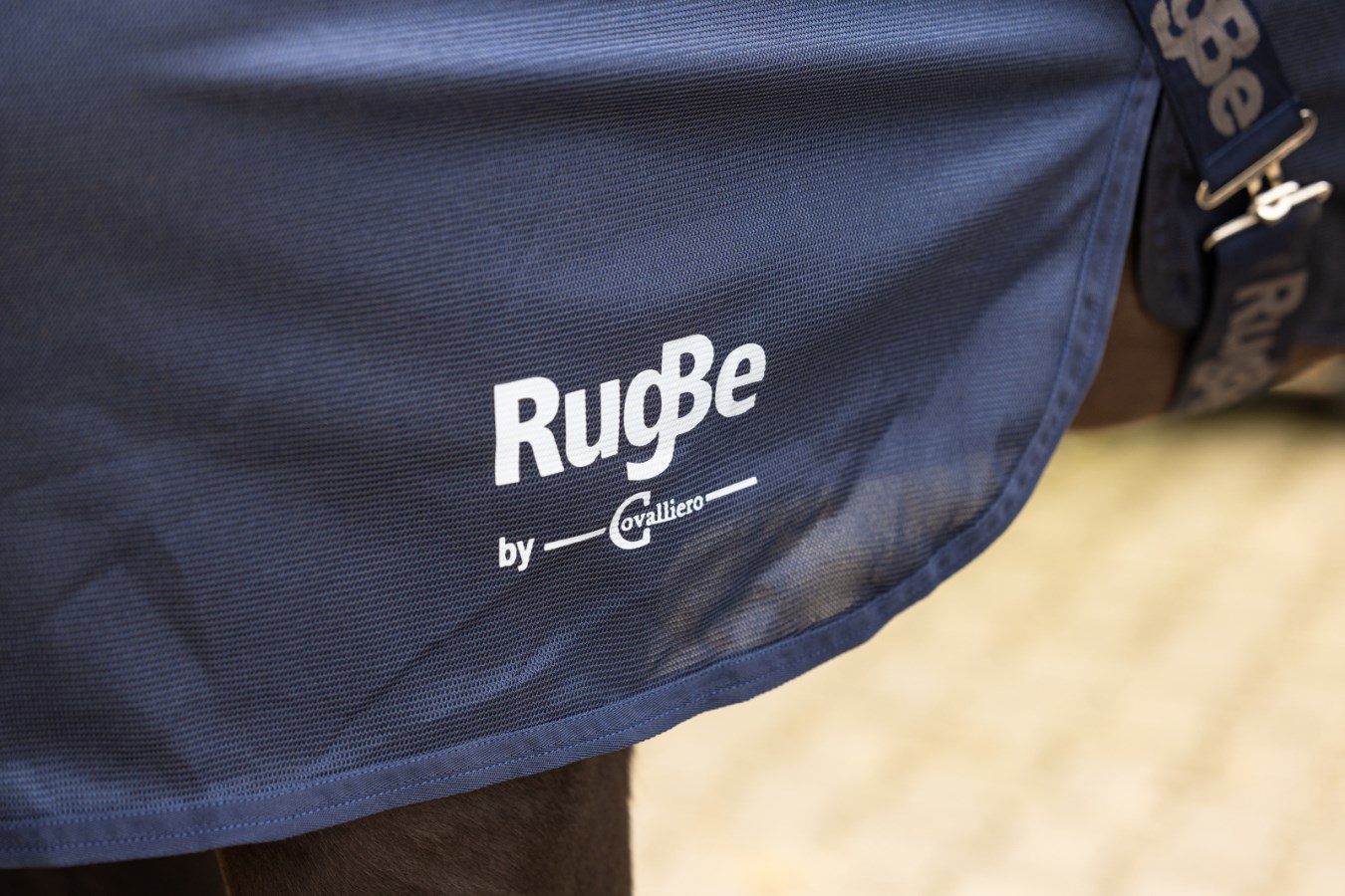 Detailansicht der navyblauen KERBL Fliegendecke RugBe SuperFly mit weißem Logo auf dem Pferderücken.