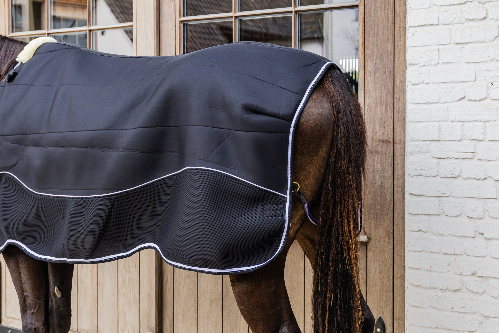 KENTUCKY® HORSEWEAR Turnout Rug Comfort 3D Fleece Liner, schwarz Schwarze Turnoutdecke Comfort 3D Fleece Liner am Pferd von der Seite, mit weißer Biese und Widerristpolster.