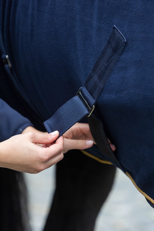 Nahaufnahme des verstellbaren Gurtverschlusses der dunkelblauen KERBL Fleecedecke RugBe Royal aus Fleece