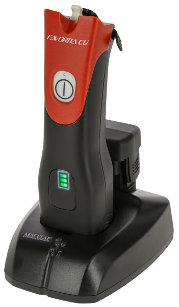 Rote Aesculap Akkuschermaschine Favorita CLi ohne Scherkopf steht in der schwarzen Ladestation mit Akkuanzeige.