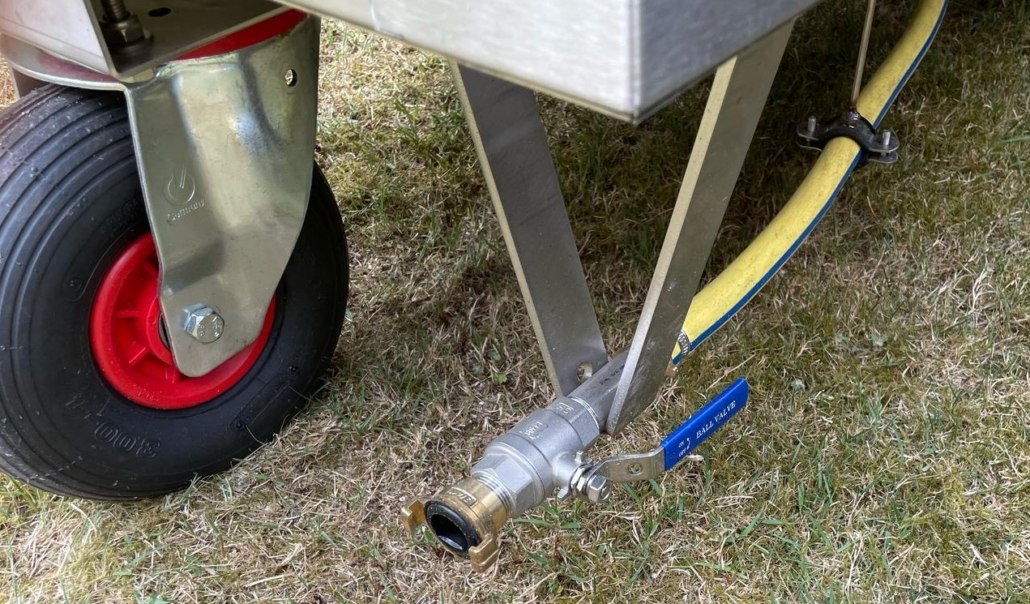 Schlauchanschluss aus Metall mit Kugelhahn und blauem Hebel, montiert am Rahmen eines Wagens neben dem Rad