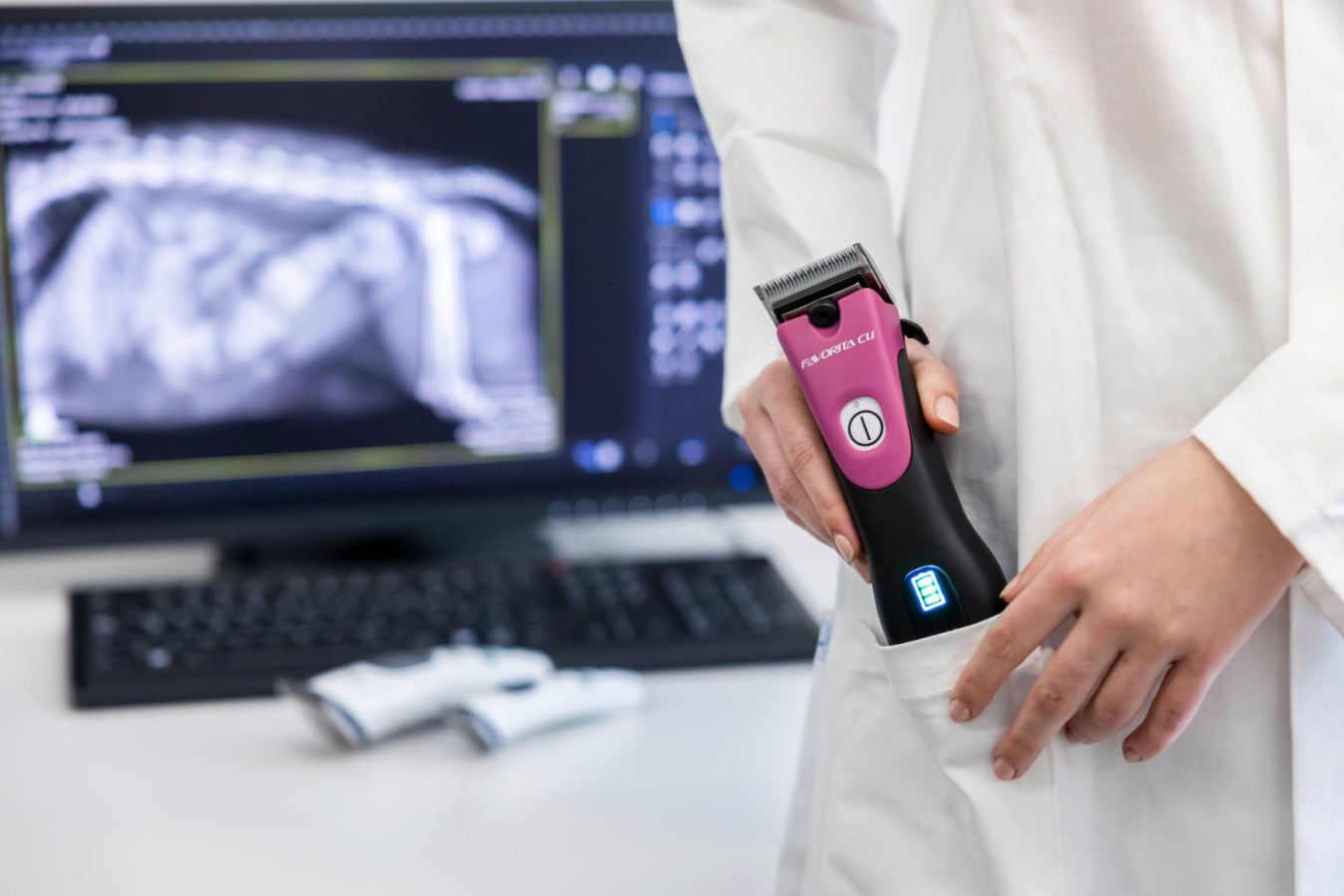 Die pink-schwarze Akkuschermaschine AESCULAP Favorita CLi wird von einer Person im Kittel in die Tasche gesteckt