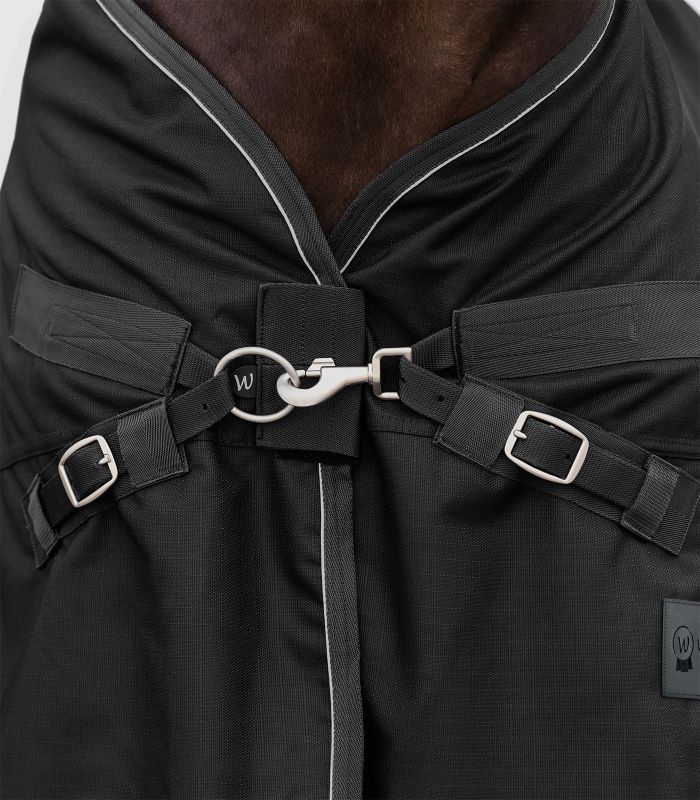 WALDHAUSEN SCANDIC Multi-Layer Outdoordecke, 250 g / 100 g, schwarz Nahaufnahme des Brustverschlusses der schwarzen SCANDIC MultiLayer Outdoordecke mit Karabinerhaken und Schnallen.