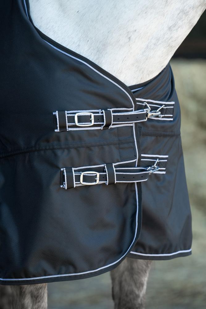 HKM Weidedecke Premium - 1680D mit glattem Futter, schwarz Schwarze Weidedecke Premium aus glattem Material mit weißer Paspelierung und doppeltem Brustverschluss am Pferd.