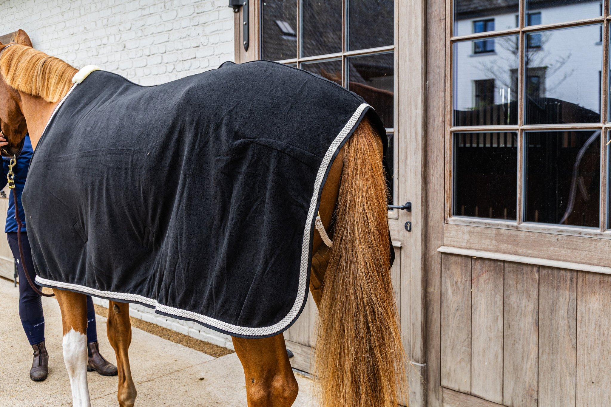 KENTUCKY® HORSEWEAR Abschwitzdecke Fleece geflochtene Kordel, schwarz Schwarze Abschwitzdecke aus Fleece mit weißer geflochtener Kordel und Widerristpolster am Pferd von der Seite
