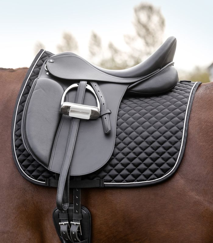 WALDHAUSEN Schabracke Felix Glam Dressur in Schwarz mit Rautensteppung und Zierkordel unter einem Sattel auf einem Pferd.