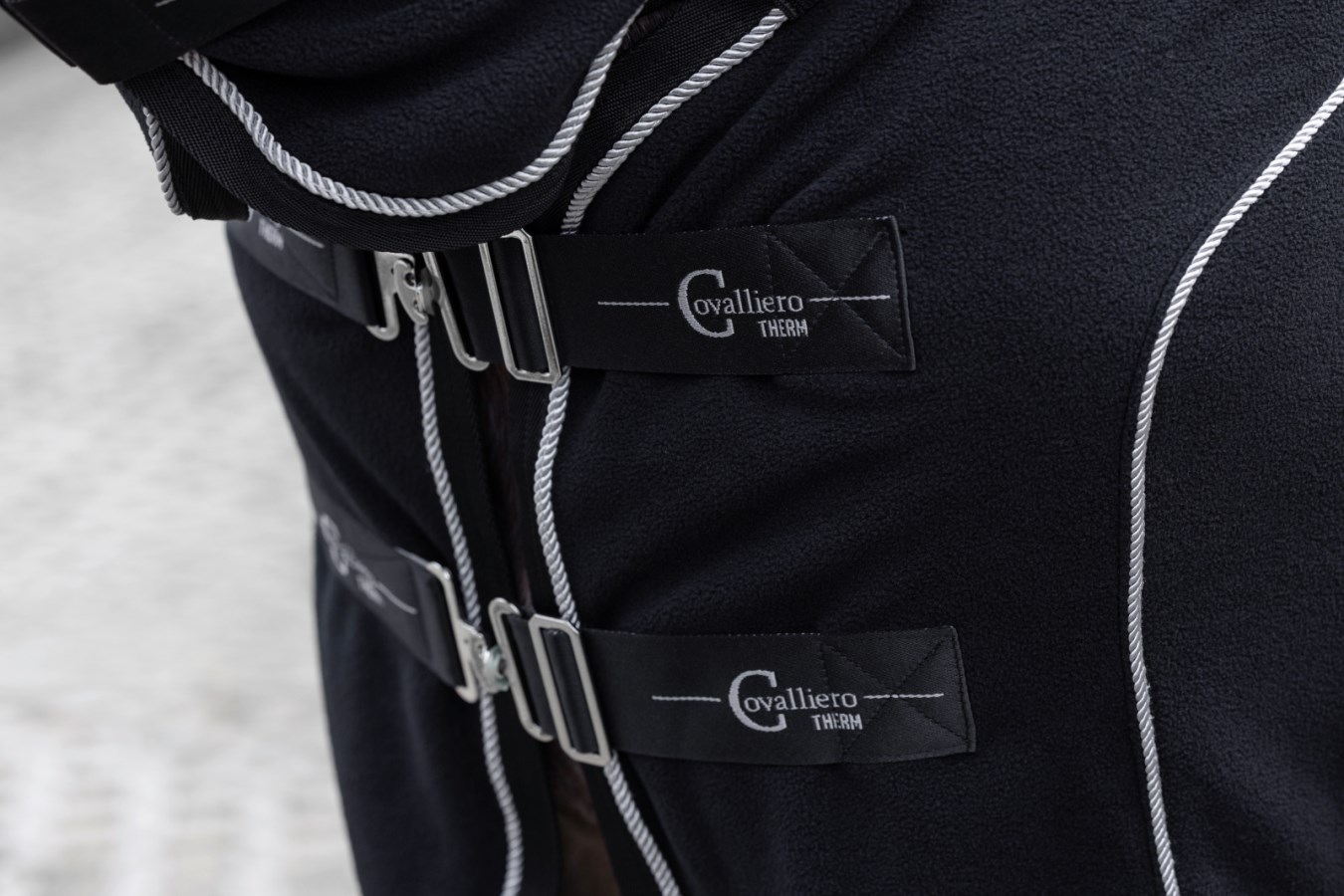 Nahaufnahme der schwarzen Fleecedecke CovallieroTherm mit Halsteil, Brustverschluss mit silbernen Schnallen.