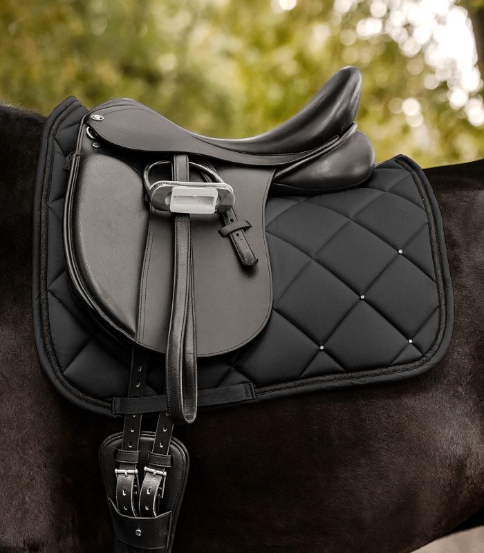 Schwarze Waldhausen Competition Dressur-Schabracke mit Rautensteppung und Strasssteinen am gesattelten Pferd.