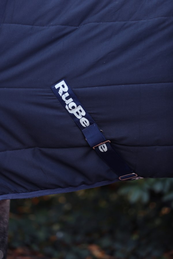 Detailansicht der dunkelblauen Kerbl Stalldecke RugBe mit gestepptem Stoff und verstellbarem Logo-Gurt.