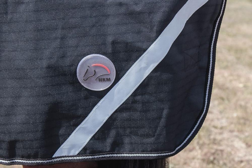 HKM Highneckdecke Innsbruck - 1200D mit Polarfleece, schwarz Detailansicht der schwarzen HKM Highneck Polarfleece Decke Innsbruck mit Ripstop-Gewebe, rundem Logo und Reflexstreifen.