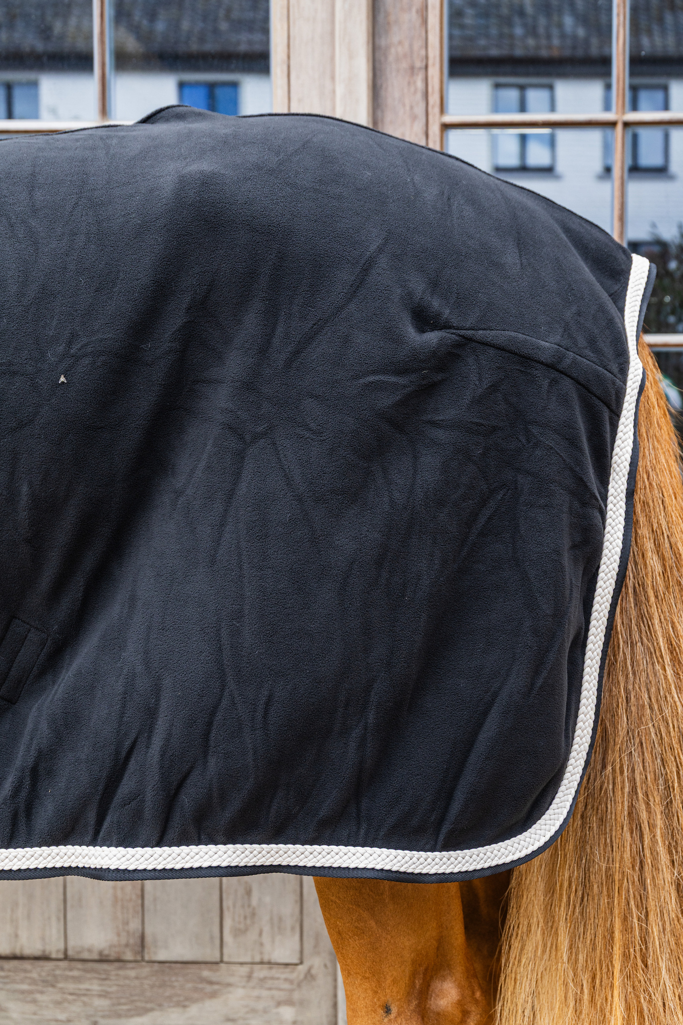 KENTUCKY® HORSEWEAR Abschwitzdecke Fleece geflochtene Kordel, schwarz Schwarze Abschwitzdecke aus Fleece mit einer weißen geflochtenen Kordel am Rand, Detailansicht auf einem Pferderücken