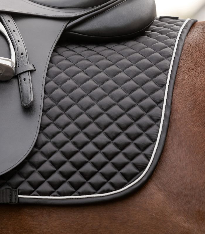 Schwarze WALDHAUSEN Dressur-Schabracke Felix Glam mit Rautensteppung und weißer Zierkordel unter einem Sattel.