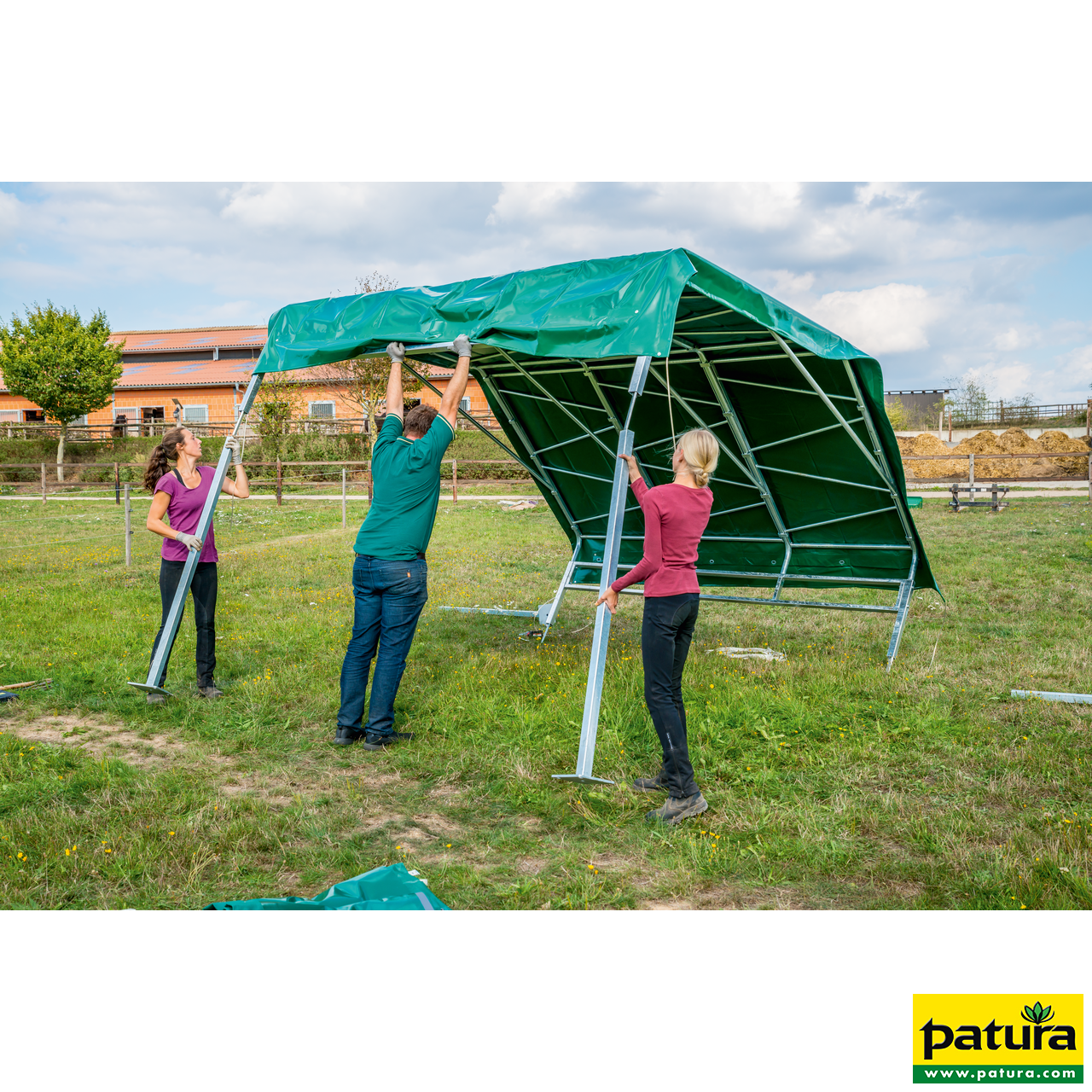 PATURA Weidezelt Profi Drei Personen montieren ein Panel-Dach mit grüner Plane und stabilem Metallgestell auf einer grünen Weide.