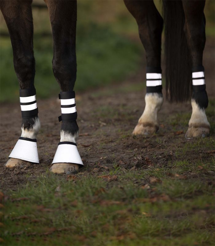 WALDHAUSEN REFLEX Bandage, Set Schwarze Waldhausen Reflex Bandagen mit zwei Leuchtstreifen und passende Hufglocken am Bein eines Pferdes.