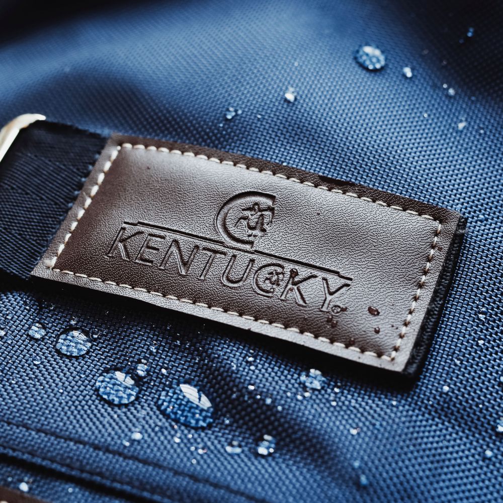 KENTUCKY® HORSEWEAR Halsteil All Weather Waterproof Pro, navy Nahaufnahme des Kentucky-Logos auf dem blauen, wasserdichten Stoff des Halsteils All Weather Pro mit abperlenden Wassertropfen.