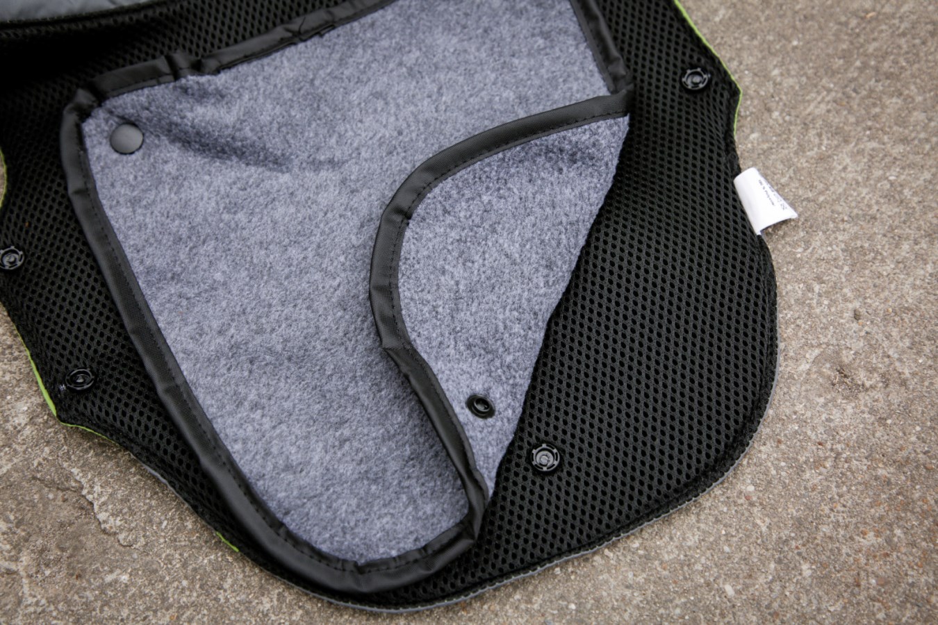 Hundemantel Vancouver mit herausnehmbarem Futter aus grauem Fleece, befestigt mit Druckknöpfen am schwarzen Mesh.