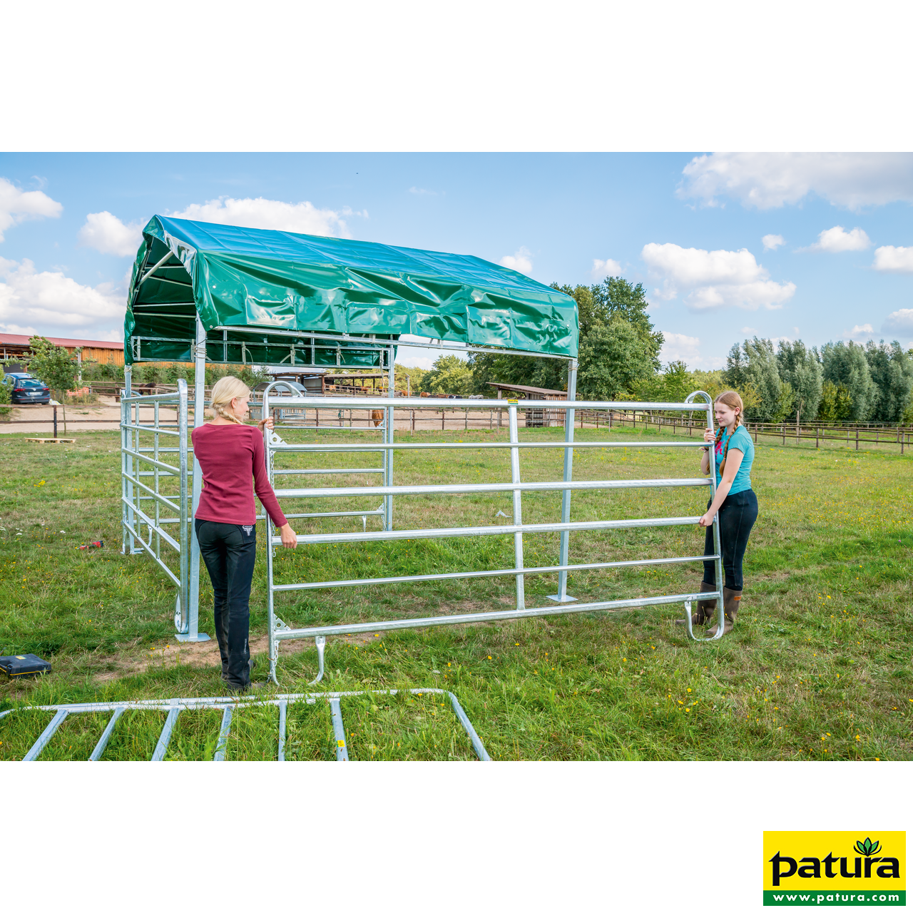 PATURA Weidezelt Profi Zwei Frauen bauen einen Weideunterstand mit grünem Panel-Dach aus verzinkten Panels auf einer Wiese auf.
