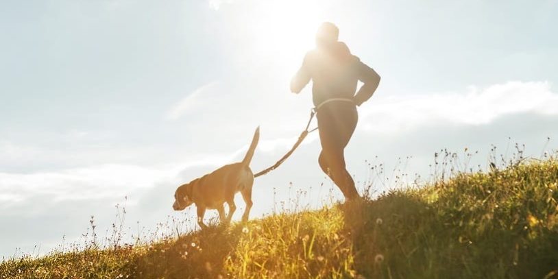 Mann joggt mit Hund an der Leine